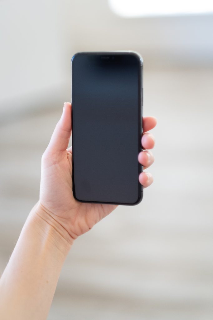 Mano con un smartphone para gestionar redes sociales de un negocio local